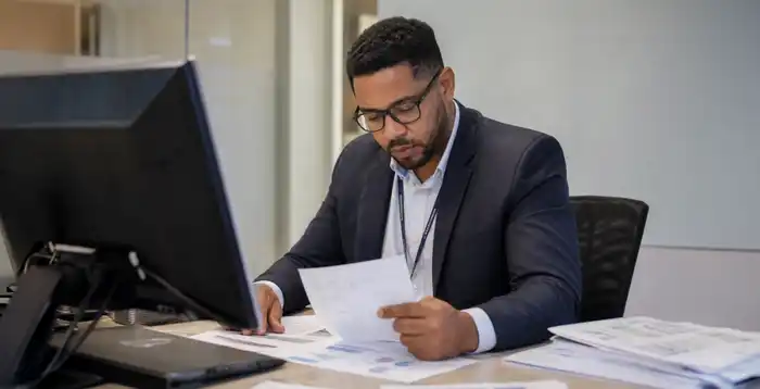 Profesional analiza documentos financieros en una oficina, representando procesos de contabilidad bancaria, análisis de crédito y evaluación financiera.